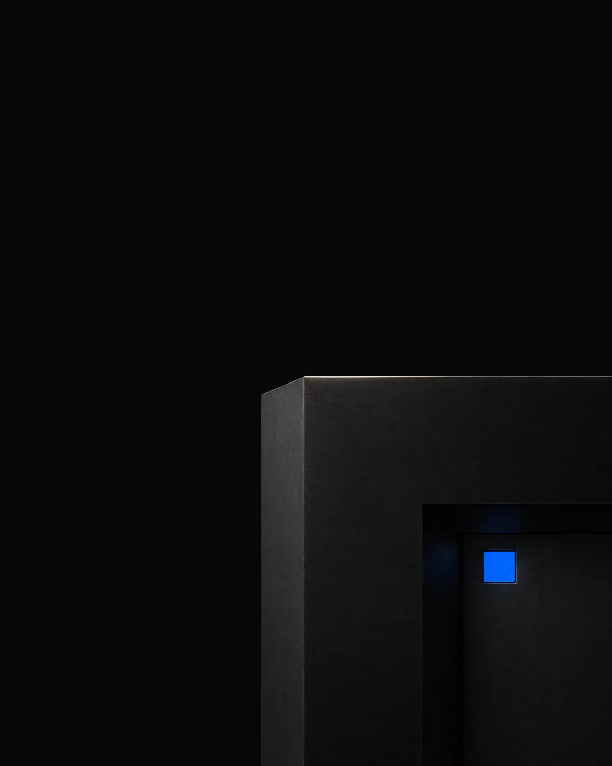 A tall crop of dark stepped blocks with one small glowing blue square near the centre